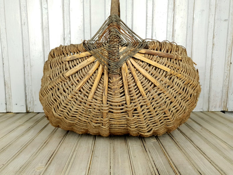 K&ouml;nnte beinhalten: Ein gro&szlig;er, geflochtener Korb aus nat&uuml;rlichen Materialien. Der Korb ist oval geformt und hat ein einzigartiges, f&auml;cherf&ouml;rmiges Design an der Oberseite. Der Korb ist braun und hat ein rustikales, vintage-m&auml;&szlig;iges Aussehen.