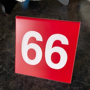 May include: A red table number with the number 66 printed in white.