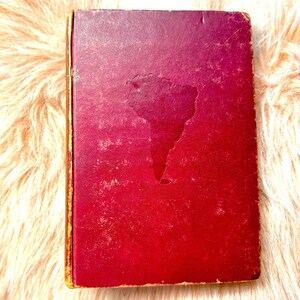 May include: A red hardcover book with a faded outline of South America on the front cover.