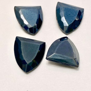 May include: Four dark blue, faceted, teardrop-shaped glass rhinestones.