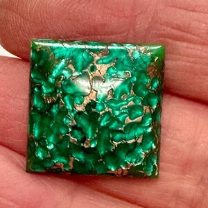 May include: A square green and gold gemstone with a marbled pattern.