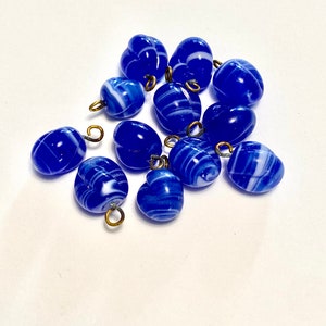 May include: A group of blue and white glass beads with gold metal loops. The beads have a swirl pattern.