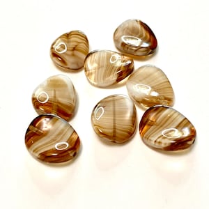 May include: Eight brown and white agate stones with a swirling pattern. The stones are smooth and polished.