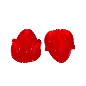 May include: Two bright red, plastic, flower-shaped candy pieces. The candy is shaped like a tulip with a rounded base and a pointed top.
