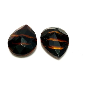 May include: Two teardrop-shaped, faceted, dark brown glass beads with a black and brown striped pattern.