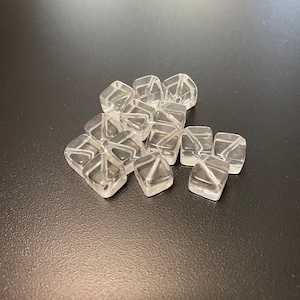 May include: A group of clear, faceted, glass dice. The dice are arranged in a loose pile on a black surface.