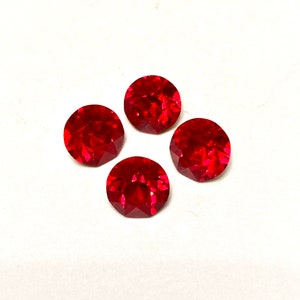 May include: Four red round gemstones with a faceted cut.