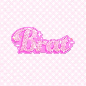 May include: A pink sticker with the word "Brat" in a glittery, bubble-style font. The sticker has a pink outline and is decorated with small starbursts. The background is a light pink pattern of white diamonds.