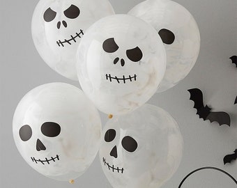 May include: A cluster of five translucent white balloons featuring a marbled texture and a printed black graphic of a skull face with hollow eyes, a triangular nose, and a stitched mouth. The balloons are arranged in a group for decoration.
