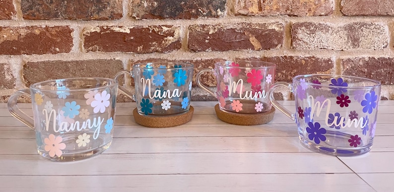 May include: Four glass mugs with floral designs and personalized names. The mugs are "Nanny", "Nana", "Mum", and "Mum". Each mug has a cork coaster.