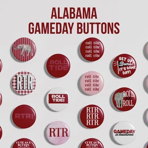 May include: A collection of circular pin-back buttons featuring the text ALABAMA GAMEDAY BUTTONS at the top. The buttons display various designs in shades of red, pink, and white, including text like ROLL TIDE, RTR, and BAMA, along with elephant graphics.