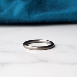 Op de afbeelding: Een eenvoudige, geborstelde zilveren trouwring. De ring is glad en heeft een matte afwerking.