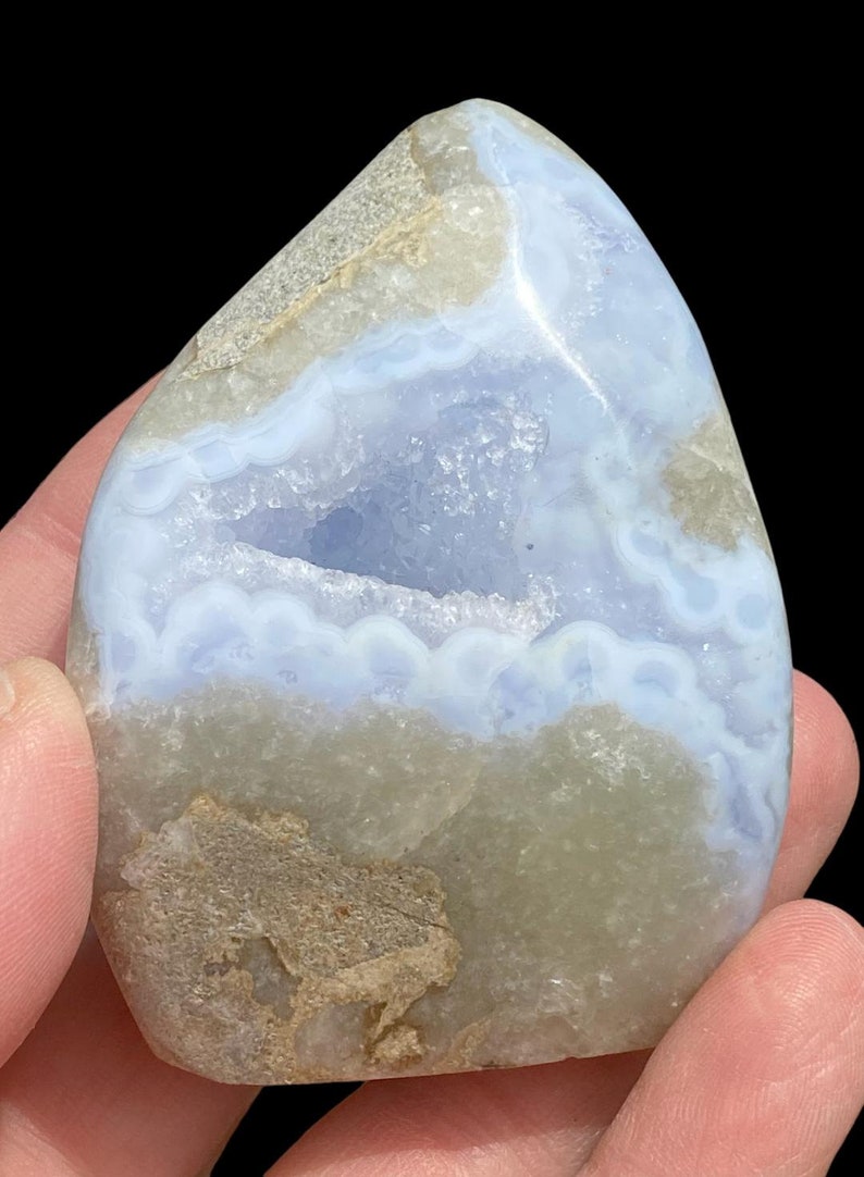 Puede incluir: Una geoda de &aacute;gata azul con una gran cavidad abierta. La geoda es de color azul claro con bandas blancas y grises. La geoda es lisa y pulida.