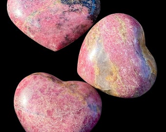 May include: Three pink and gold heart-shaped polished stones. The stones have a marbled pattern and are smooth to the touch.