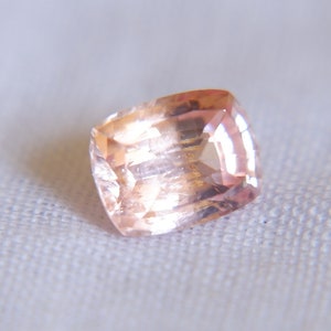 May include: A light pink gemstone with a rectangular shape and a faceted cut.