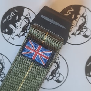 May include: Close-up of an olive green watch strap with a small Union Jack patch. The strap has a black buckle with a knife design. The background features a logo with the text "NX STRAPS".