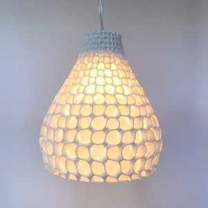 Pode incluir: Luminária pendente branca com um design único, orgânico, em forma de favo de mel. A luminária é feita de um material branco e tem uma forma de pêra.