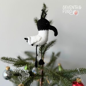 A crochet Ibis bird wearing a santa hat and a christmas light garden. Also known by the Australian term for the bird, bin chicken