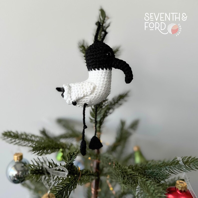 A crochet Ibis bird wearing a santa hat and a christmas light garden. Also known by the Australian term for the bird, bin chicken