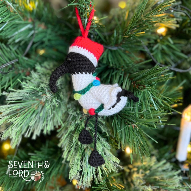 A crochet Ibis bird wearing a santa hat and a christmas light garden. Also known by the Australian term for the bird, bin chicken