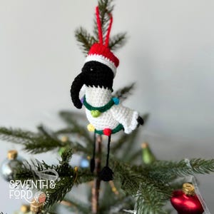 A crochet Ibis bird wearing a santa hat and a christmas light garden. Also known by the Australian term for the bird, bin chicken