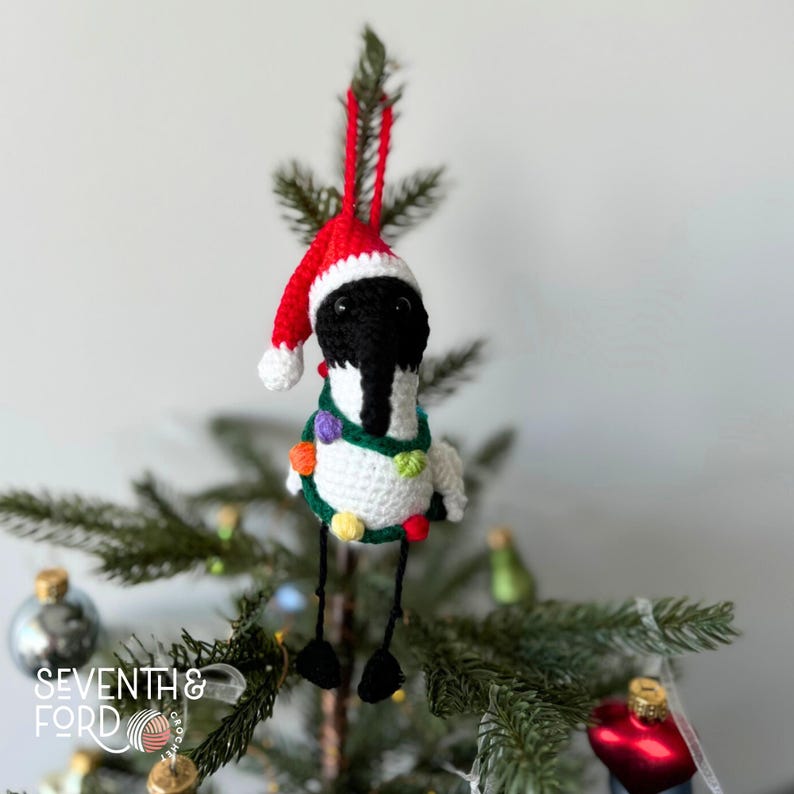 A crochet Ibis bird wearing a santa hat and a christmas light garden. Also known by the Australian term for the bird, bin chicken