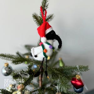A crochet Ibis bird wearing a santa hat and a christmas light garden. Also known by the Australian term for the bird, bin chicken
