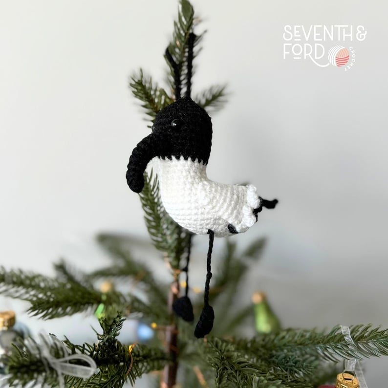 A crochet Ibis bird wearing a santa hat and a christmas light garden. Also known by the Australian term for the bird, bin chicken