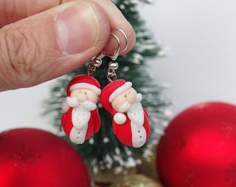 May include: A pair of red and white Santa Claus earrings with silver hooks. The earrings are made of polymer clay and are a festive holiday accessory.