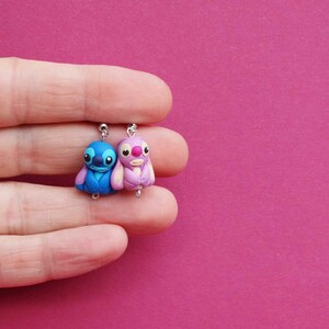 May include: A pair of blue and pink Stitch character earrings. The earrings are made of polymer clay and feature the iconic Stitch character from the Disney movie Lilo & Stitch.