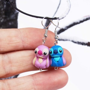May include: A pair of dangle earrings featuring Stitch and Angel from the Disney movie Lilo & Stitch. The earrings are made of polymer clay and have silver hooks.