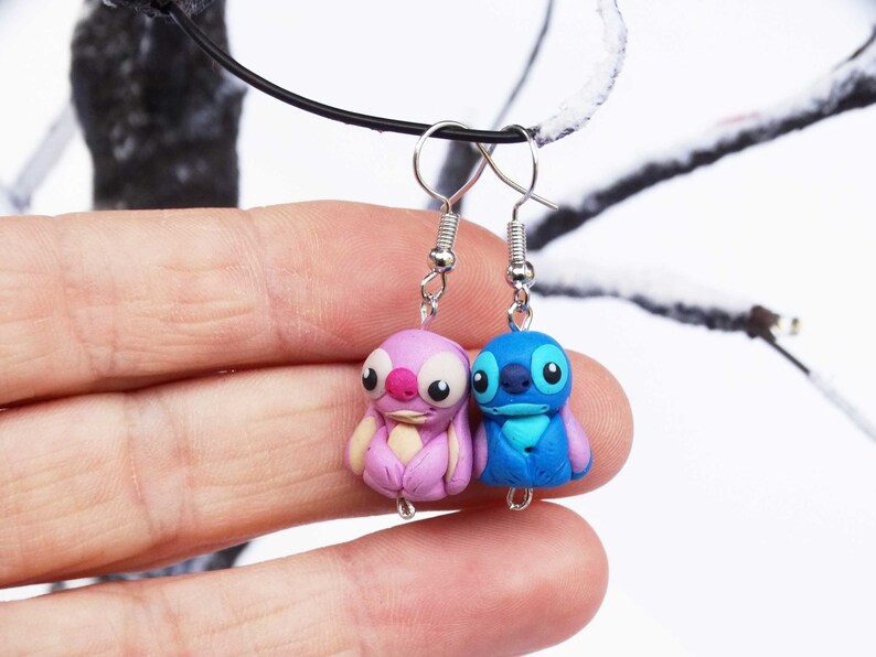 May include: A pair of dangle earrings featuring Stitch and Angel from the Disney movie Lilo & Stitch. The earrings are made of polymer clay and have silver hooks.