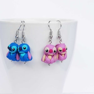 May include: A pair of blue and pink Stitch character earrings. The earrings are made of polymer clay and feature the iconic Stitch character from the Disney movie Lilo & Stitch.