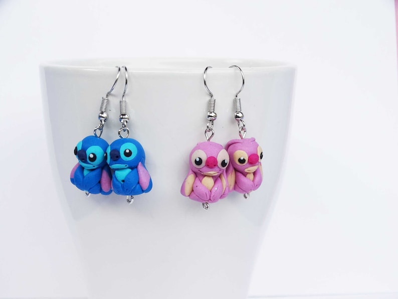 May include: A pair of blue and pink Stitch character earrings. The earrings are made of polymer clay and feature the iconic Stitch character from the Disney movie Lilo & Stitch.