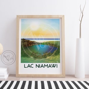 May include: Framed art print featuring a colorful landscape of Lac Niamawi. The artwork is displayed in a light wood frame and includes the text "LAC NIAMAWI". The print is set against a white wall with a black and white striped rug.