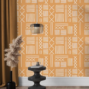 Peut inclure: Papier peint moutarde avec un motif géométrique répétitif de lignes, de croix et de rectangles blancs. Le design crée un aspect texturé d'inspiration tribale. La pièce comprend également une table d'appoint noire, un vase noir avec des plantes séchées et une suspension.