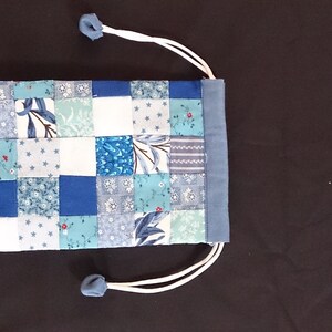 May include: A small blue and white patchwork drawstring bag with a white cord.