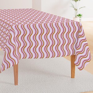 May include: A pink and brown tablecloth with a wavy pattern. The tablecloth is draped over a table with wooden legs.