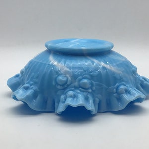 May include: A blue and white milk glass bowl with a ruffled edge and a swirl design. The bowl is decorated with raised roses.