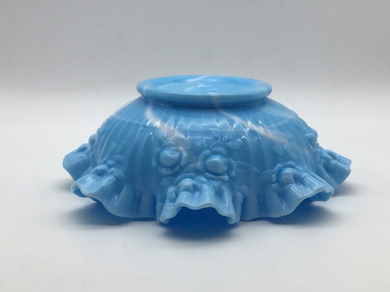 May include: A blue and white milk glass bowl with a ruffled edge and a swirl design. The bowl is decorated with raised roses.