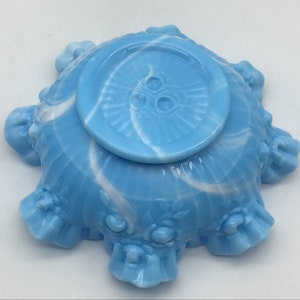 May include: A blue and white swirl glass bowl with a ruffled edge and floral design. The bowl has a smooth, glossy finish.