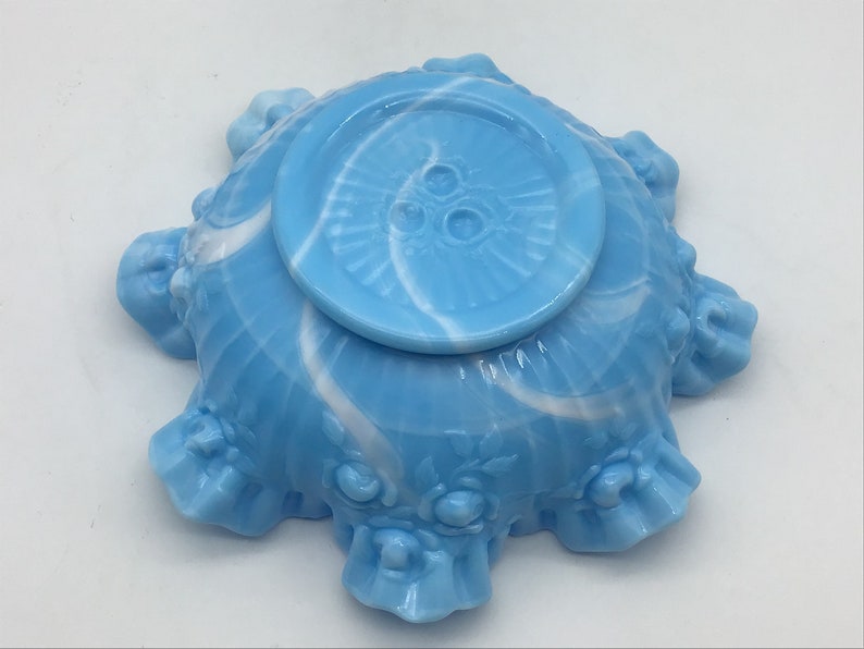 May include: A blue and white swirl glass bowl with a ruffled edge and floral design. The bowl has a smooth, glossy finish.