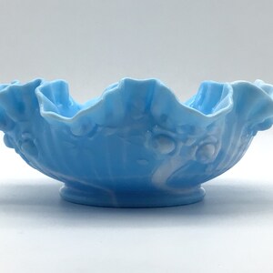 May include: A light blue glass bowl with a ruffled edge and a white floral design.