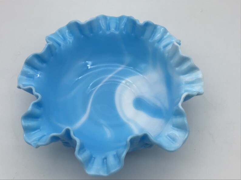 May include: A blue and white swirl glass bowl with a ruffled edge.