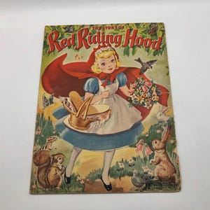 May include: A vintage children's book cover featuring a girl in a red hooded cloak and a basket. The title of the book is "The Story of Red Riding Hood".