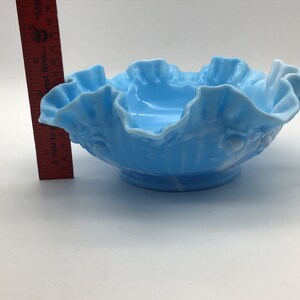 May include: A light blue glass bowl with a ruffled edge and a floral design. The bowl is approximately 5 inches in diameter.