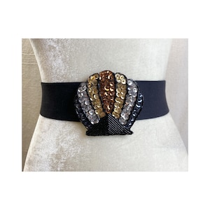 May include: A black elastic belt with a large, gold, silver, and black sequined seashell design.