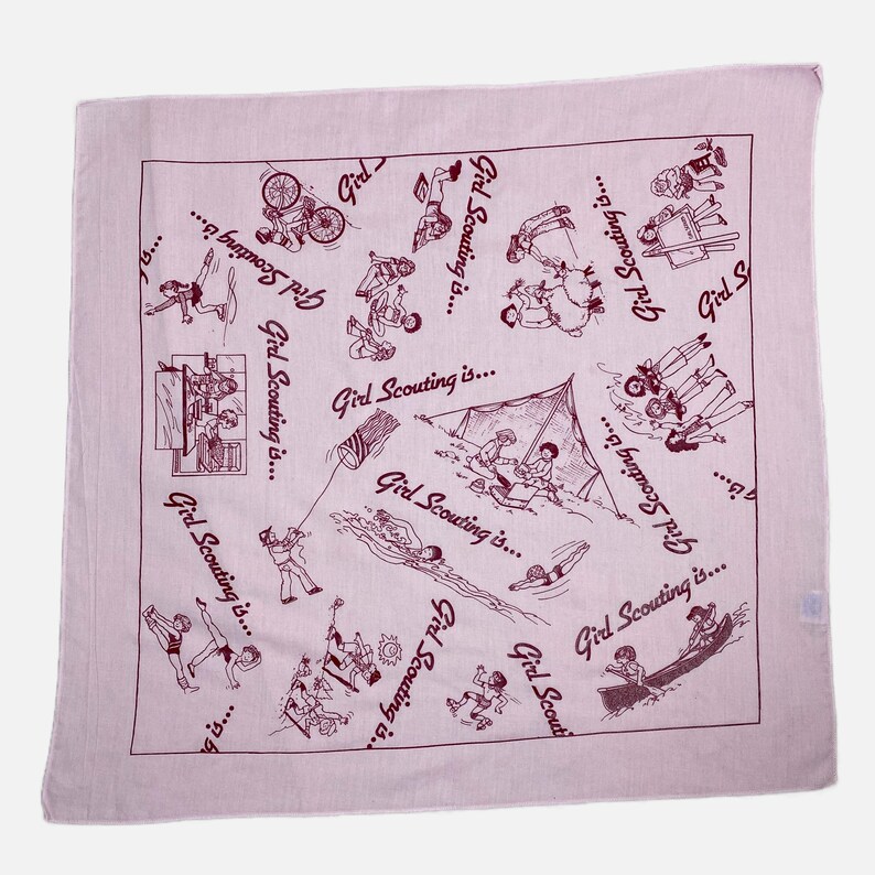 May include: A light pink square bandana with a repeating pattern of line drawings depicting various outdoor activities. The phrase "Girl Scouting is..." is written in a cursive font throughout the design.
