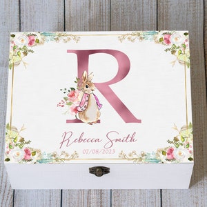 May include: White wooden keepsake box with a gold trim and floral design. A large pink letter "R" is displayed with a watercolour illustration of a bunny. The name "Rebecca Smith" and the date "07/08/2023" are also shown.