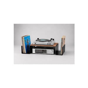 May include: A black metal audio equipment stand with a wooden top shelf. The stand holds a silver turntable on top and a silver receiver underneath. Two black metal record dividers are positioned on either side, each holding a collection of vinyl records.